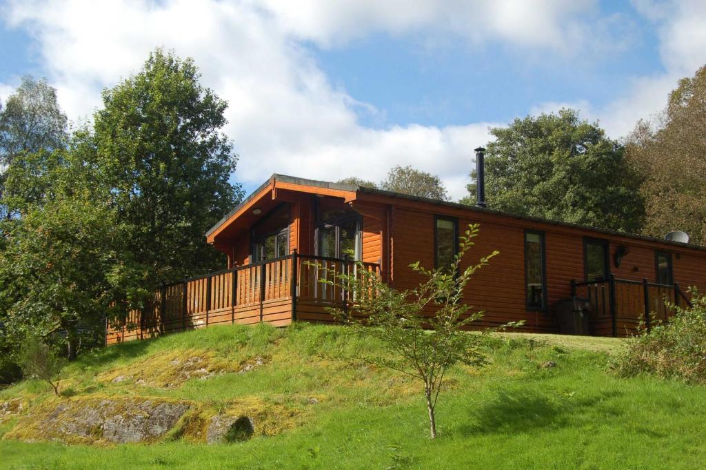 uma cabana de madeira numa colina com árvores em Luxury woodland Oak Lodge em Killin