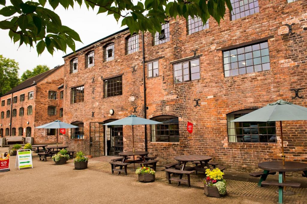 a brick building with tables and umbrellas in front of it at YHA Ironbridge Coalport in Coalport