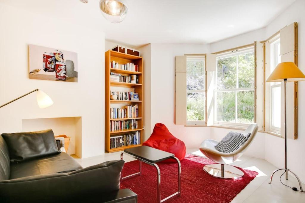 a living room with a couch and a red rug at Stylish bright apartment w private garden in London