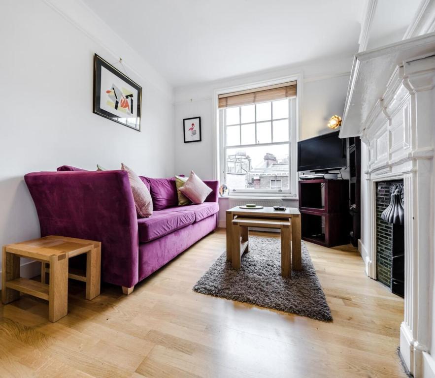 a living room with a purple couch and a table at Stylish 1 Bedroom Apartment in Amazing Soho Location in London