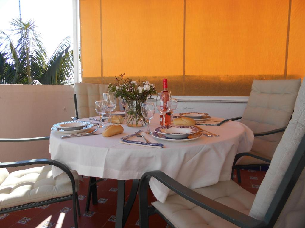 uma mesa com uma toalha de mesa branca e flores sobre ela em 300-Meter-bis-zum-Strand-Caracola-Wohnung-mit-Garten em Chipiona