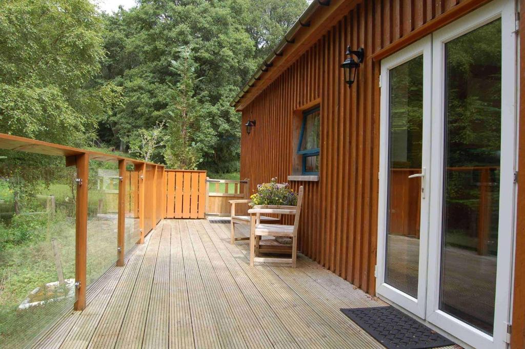 a large wooden deck next to a house at Waterfall Lodge - private waterfall and sauna in Killin