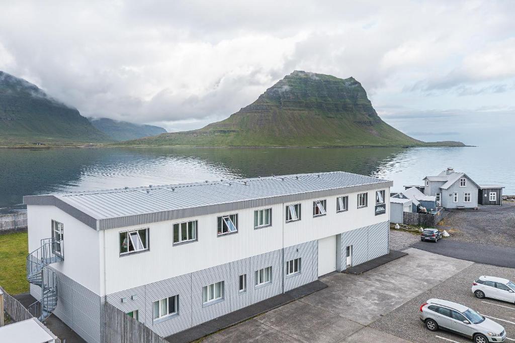 a white building next to a body of water at Stöð Guesthouse and apartments in Grundarfjordur