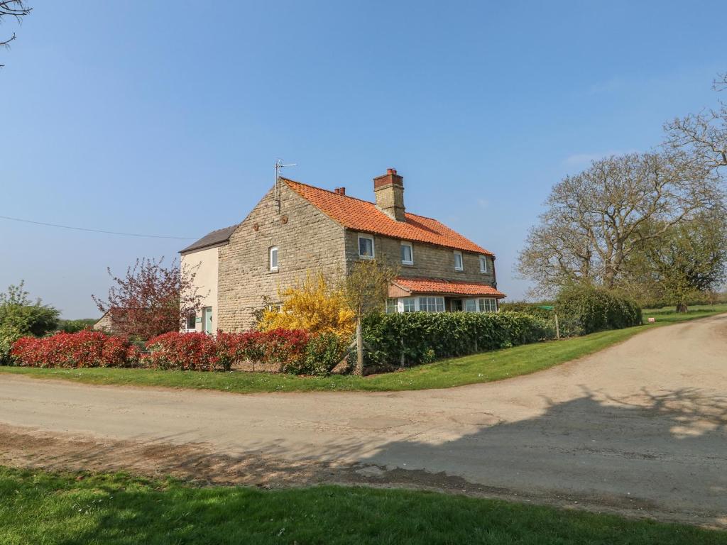 a house on a dirt road next to a driveway at Grange Farm Cottage in Sleaford