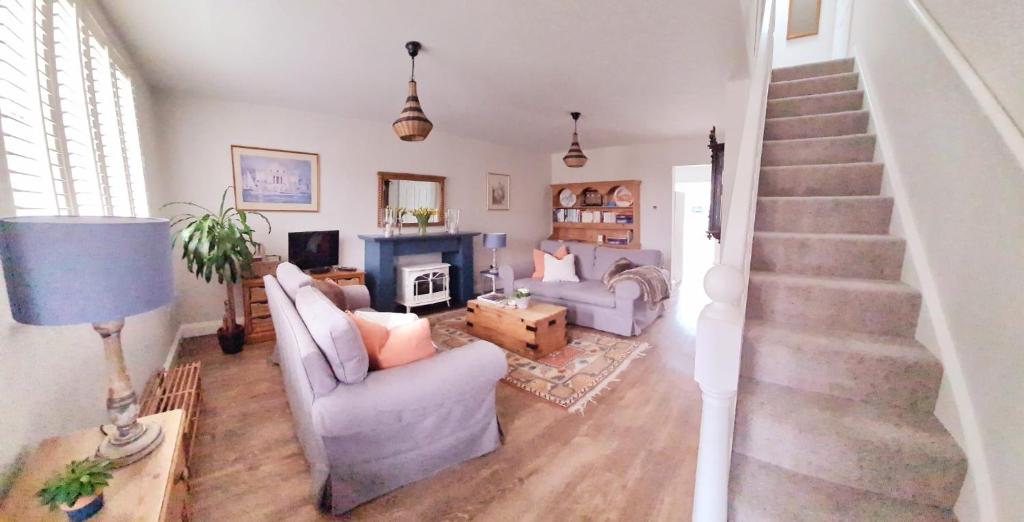 a living room with a staircase with a couch and a fireplace at The Olives in Holt