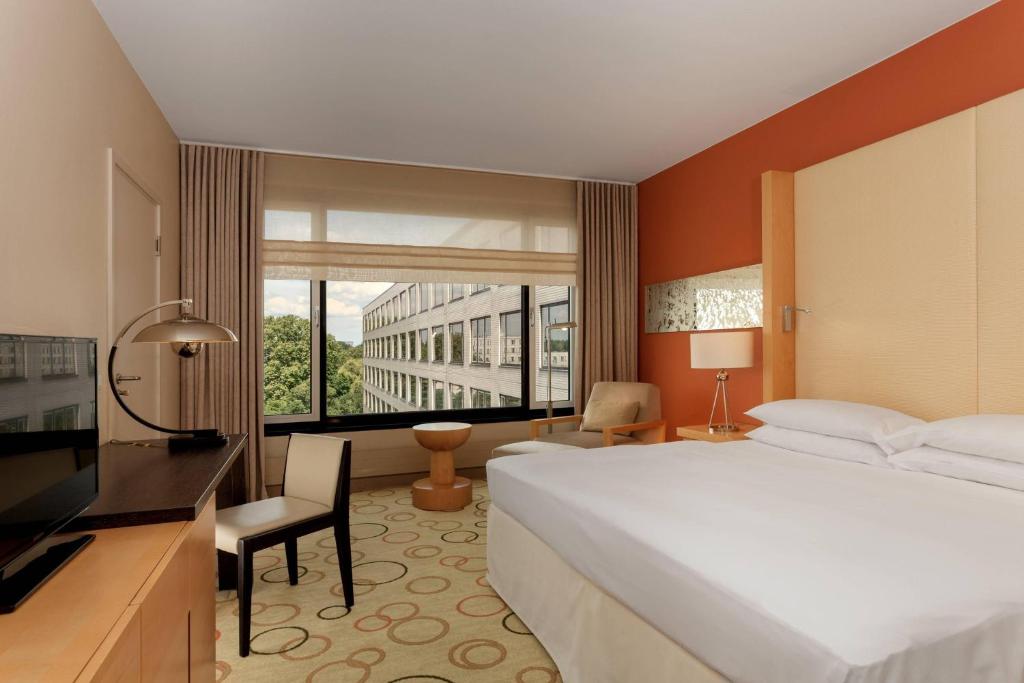 um quarto de hotel com uma cama grande e uma janela em Sheraton Berlin Grand Hotel Esplanade em Berlim