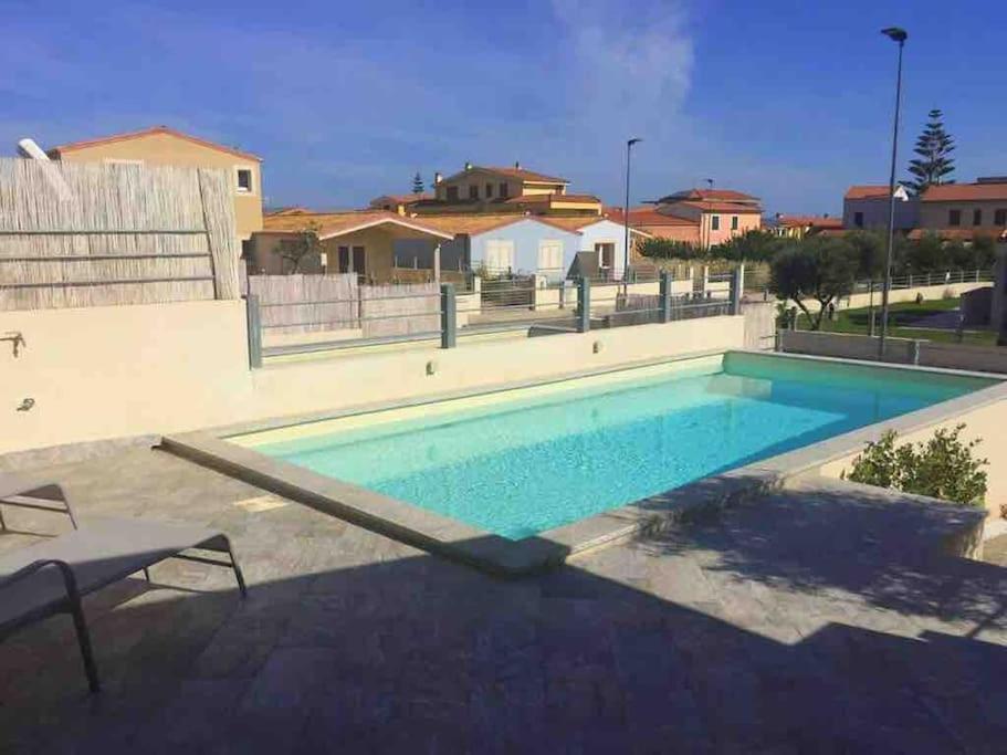 a large swimming pool in a yard with houses at Villa Etienne - Key to Villas in Valledoria