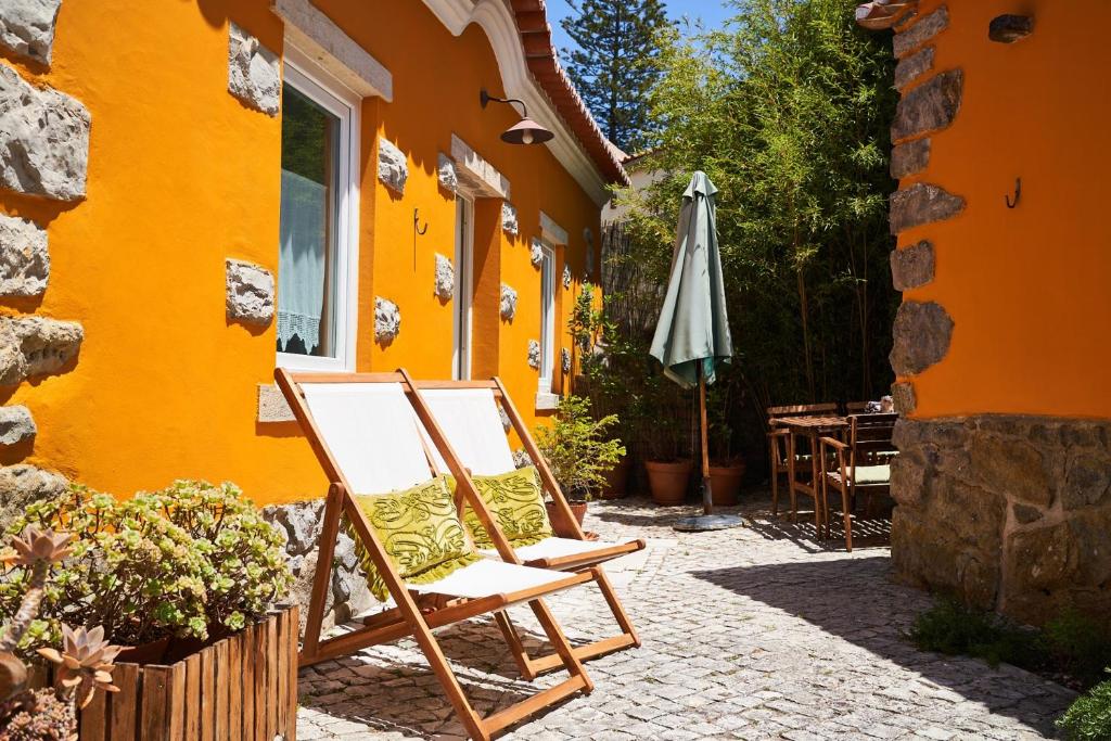 an orange building with a chair and an umbrella at Sparrow Sintra Nest in Sintra