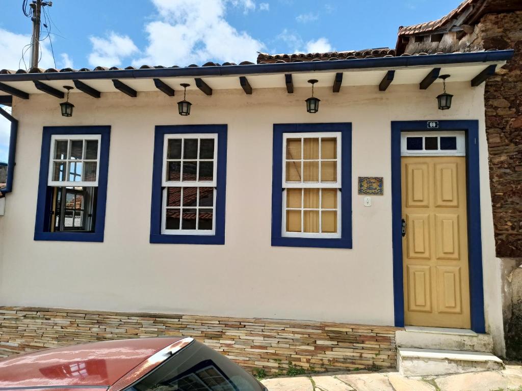 a white and blue house with a yellow door at Casa da Kau in Ouro Preto