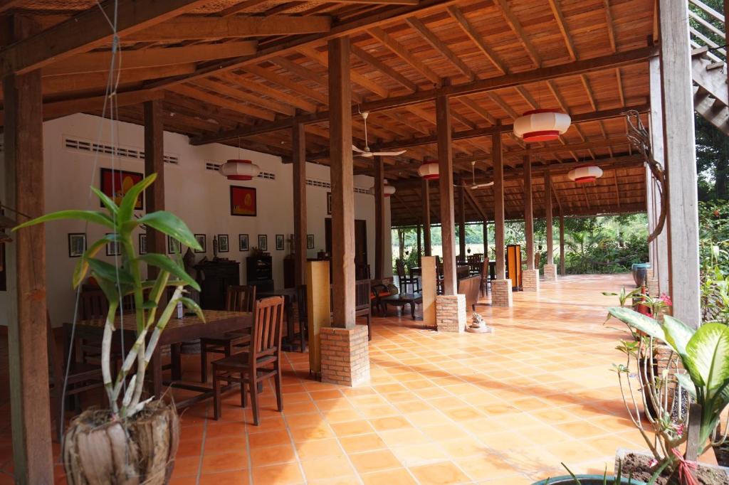 Großes Zimmer mit einem Tisch, Stühlen und Pflanzen in der Unterkunft Arun Mekong Guesthouse in Kratie