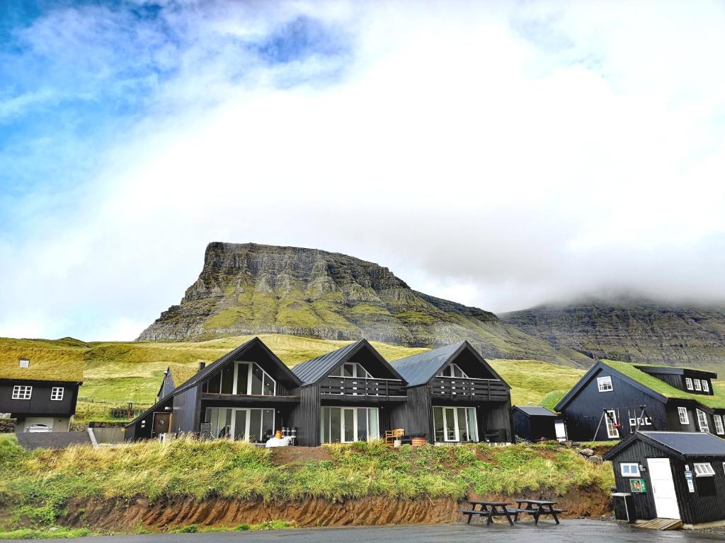 a black house with a mountain in the background at Gásadalur Apartments @ World famous waterfall in Gásadalur