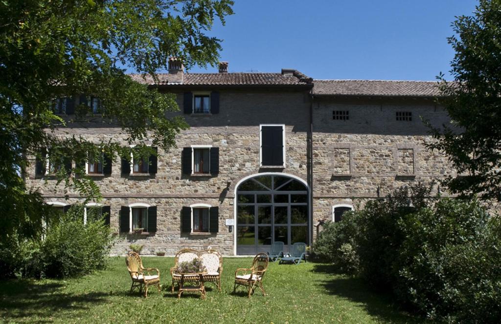 un antiguo edificio de piedra con sillas en el patio en Agriturismo Il Brugnolo, en Scandiano