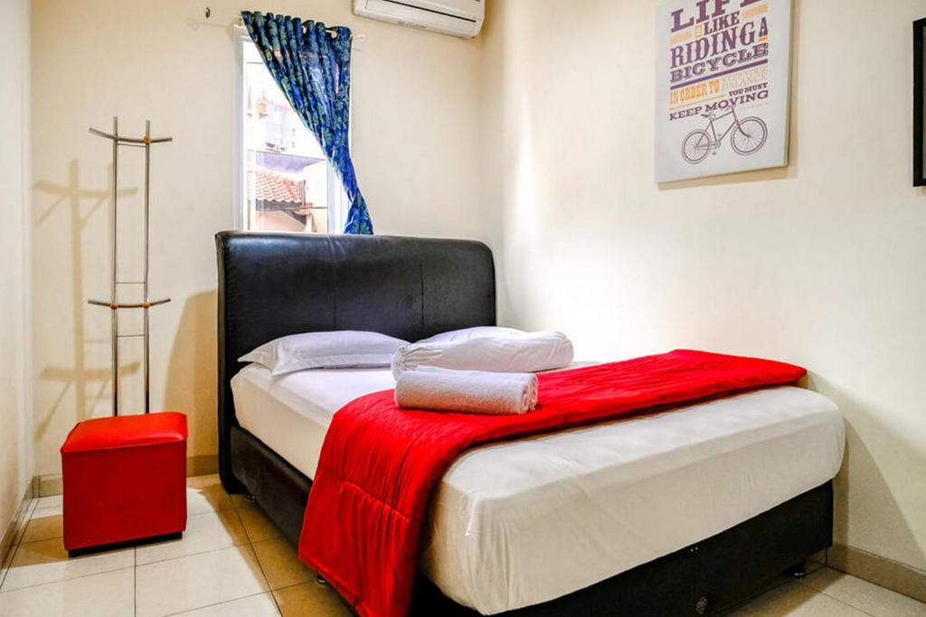 a bedroom with a bed with a red blanket on it at Pondok Malabar Mitra RedDoorz in Jakarta