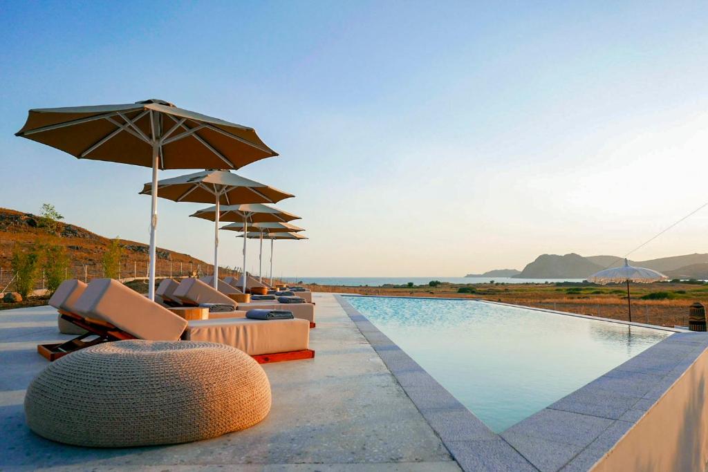 una piscina con tumbonas y sombrillas junto al océano en Amaranto Evgatis Limnos, en Kondiás