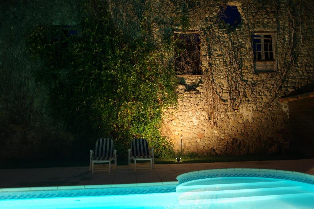 - deux chaises assises à côté de la piscine la nuit dans l'établissement L'Impasse du Temple, à Léran