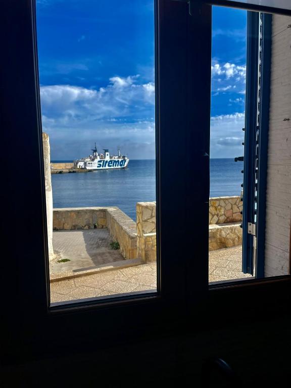 a window with a view of a boat in the water at Il Muretto in Marettimo