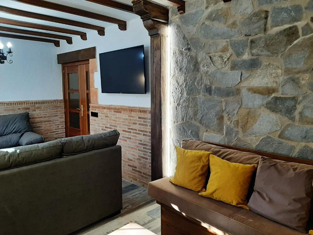 sala de estar con sofá y pared de piedra en Casa Rural El Arroyo en Sotoserrano