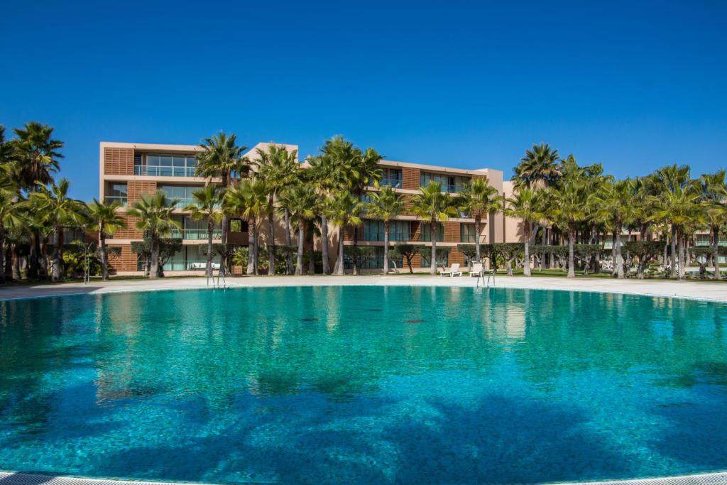 een groot zwembad met palmbomen voor een gebouw bij Anchor Apartment - Herdade dos Salgados & Luxurious & 7 Pools & Golf in Albufeira