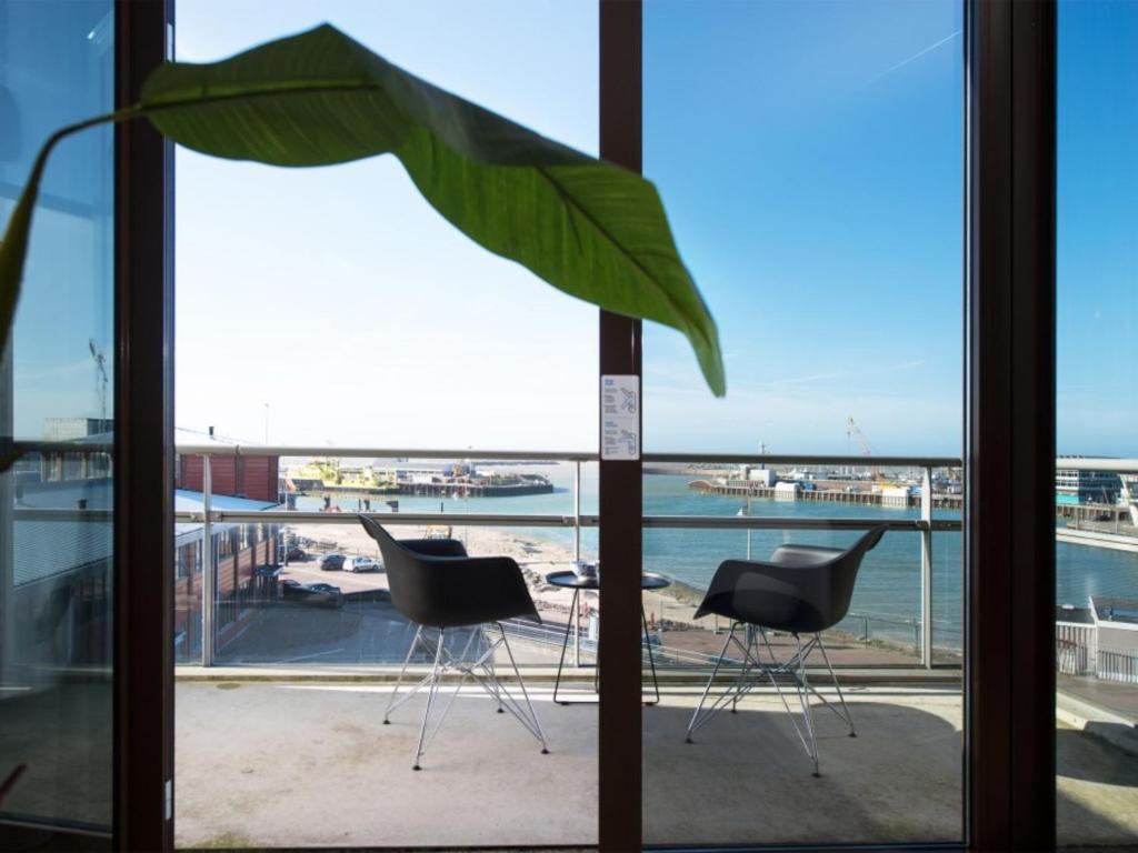 une fenêtre avec deux chaises et une vue sur l'océan dans l'établissement Luxury apartment near Scheveningen beach, à Scheveningen