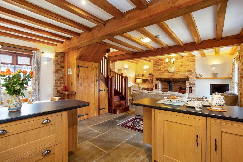 a kitchen with wooden cabinets and a living room at Shire Cottage in Broadway