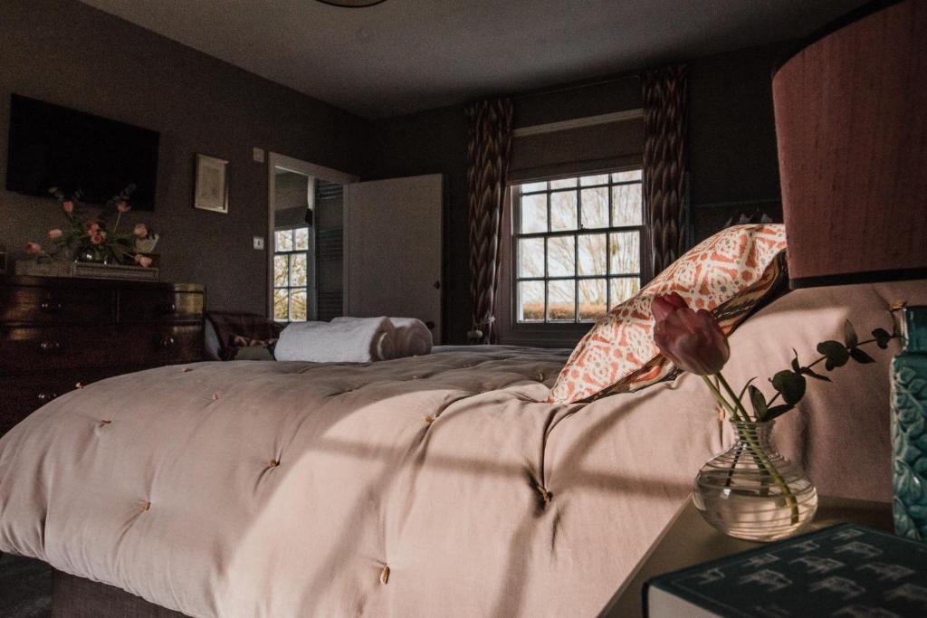 ein Schlafzimmer mit einem Bett und einer Vase mit einer Blume in der Unterkunft The Naight House in Gloucester