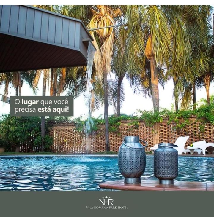 two vases sitting on a table next to a swimming pool at Vila Romana Park Hotel in Três Lagoas