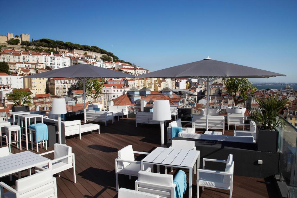 a restaurant with white chairs and tables and umbrellas at Hotel Mundial in Lisbon