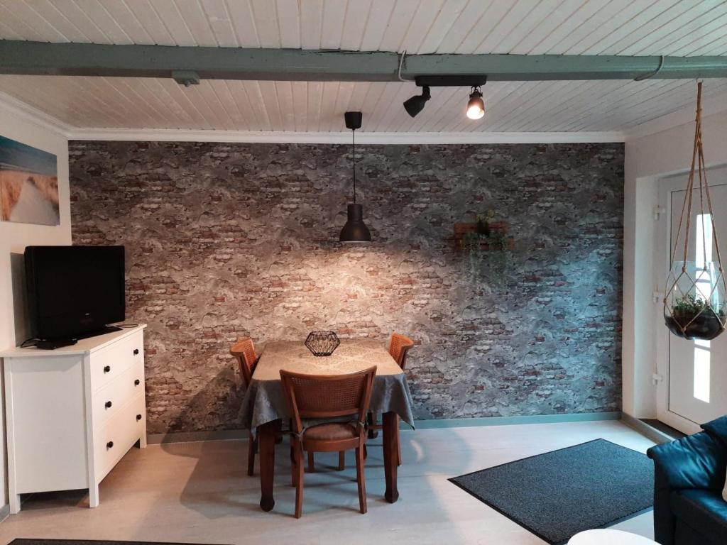 a dining room with a table and a brick wall at Holiday Nr,3 in Immenstedt
