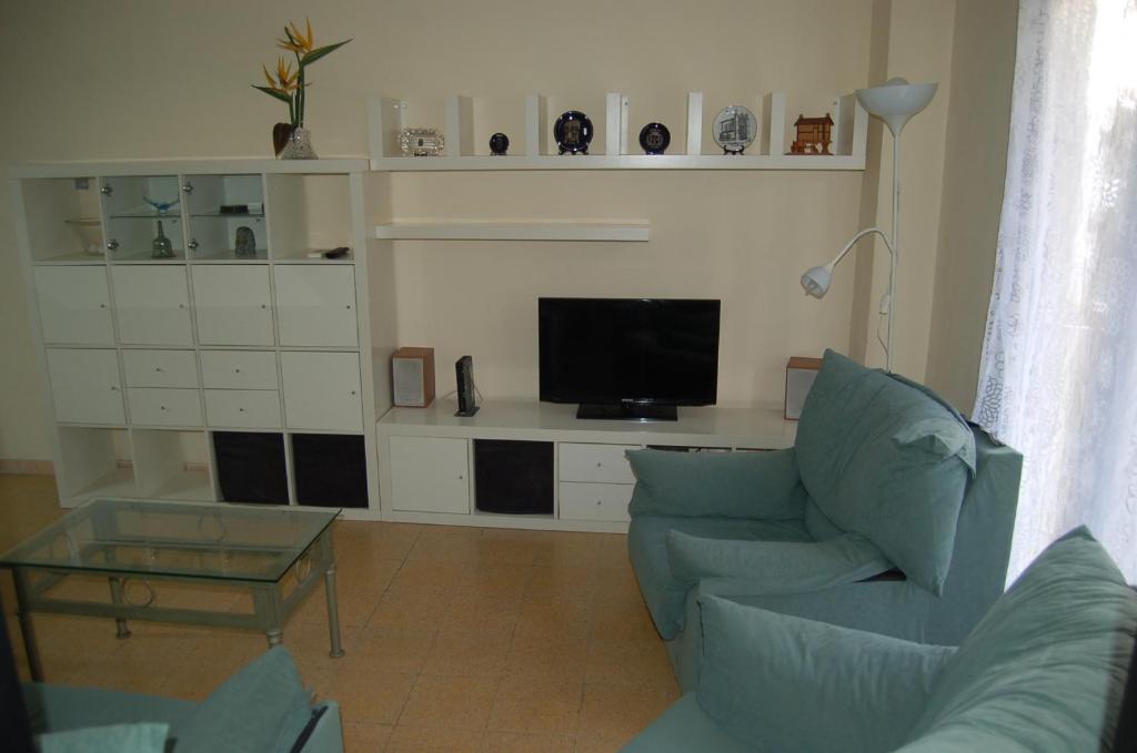 sala de estar con sofá azul y TV en Hortes 7, en Girona