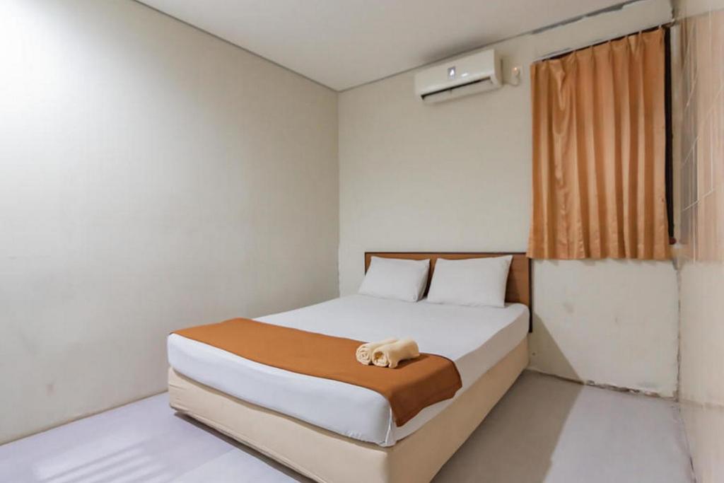 una camera da letto con un letto e un asciugamano sopra di Mahkota Intan Syariah Balikpapan RedPartner a Balikpapan