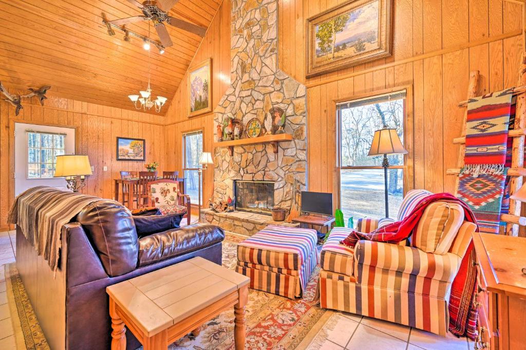 a living room with two couches and a stone fireplace at Serene Cabin with Riverfront Views and Access! in Fayetteville