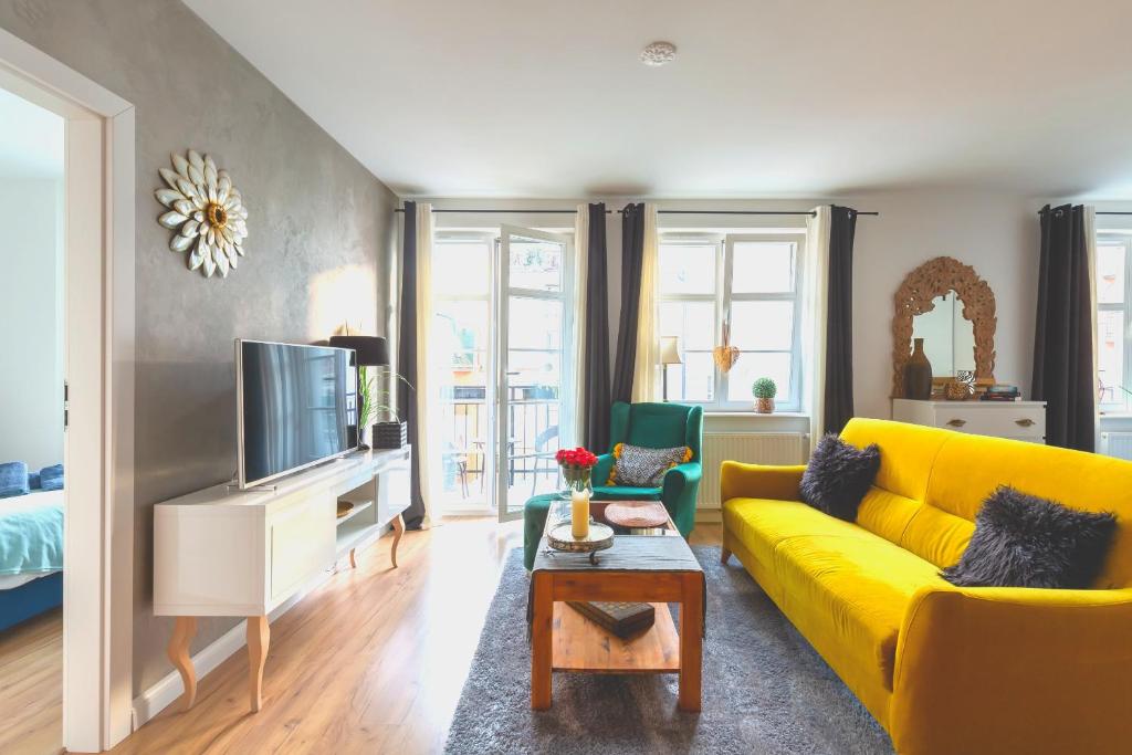 Bea Home Elblag - dwie sypialnie في البلاج: غرفة معيشة مع أريكة صفراء وتلفزيون