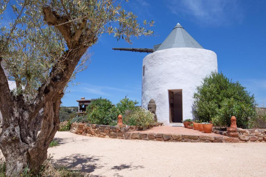 una iglesia con un molino de viento en medio de un campo en Moinho Calmo en Vila do Bispo