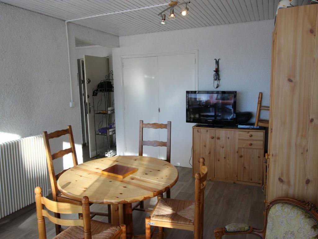 a dining room with a wooden table and a television at Appartement Chamrousse, 2 pièces, 5 personnes - FR-1-549-84 in Chamrousse