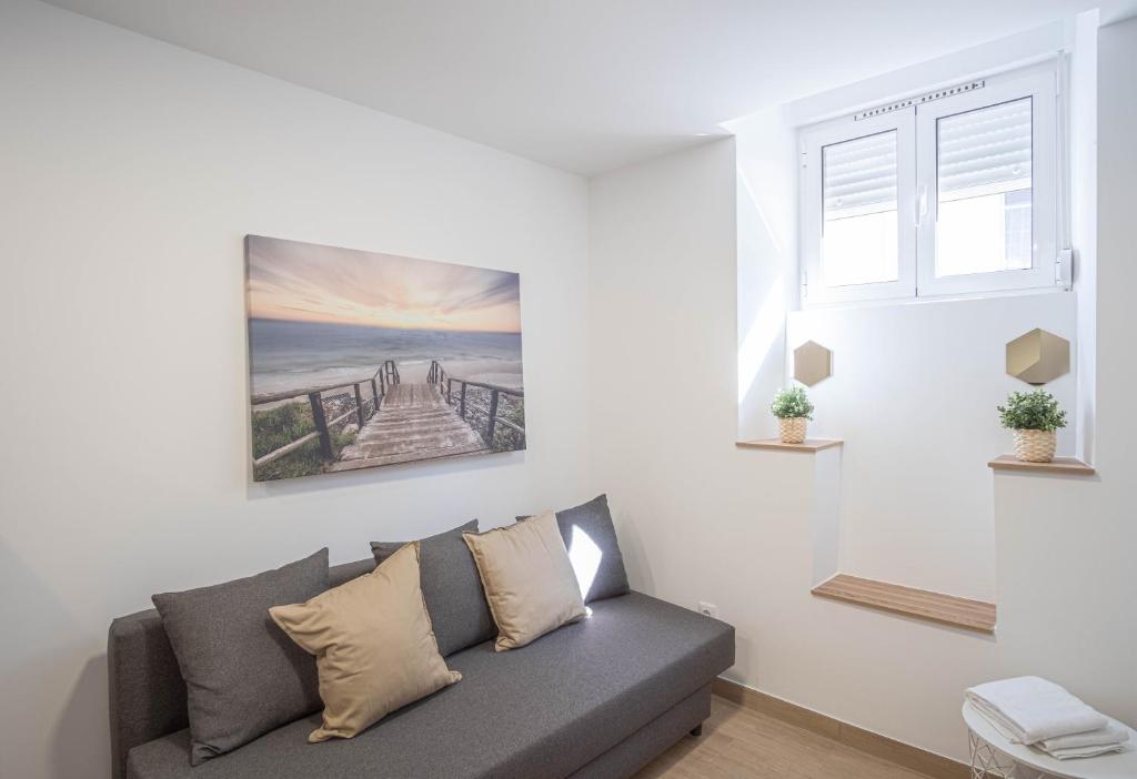 Belem Studio - Near Main Touristic Area في لشبونة: غرفة معيشة مع أريكة وصورة على الحائط