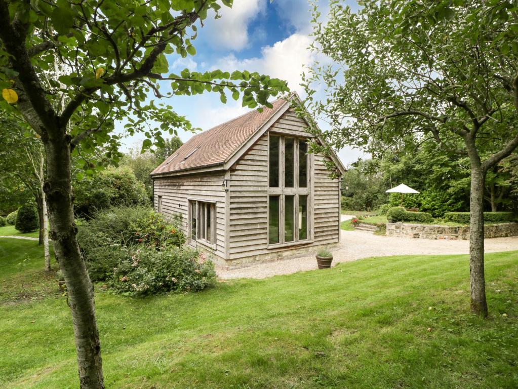 una vieja cabaña en un patio con árboles en The Barn at Frog Pond Farm en Salisbury