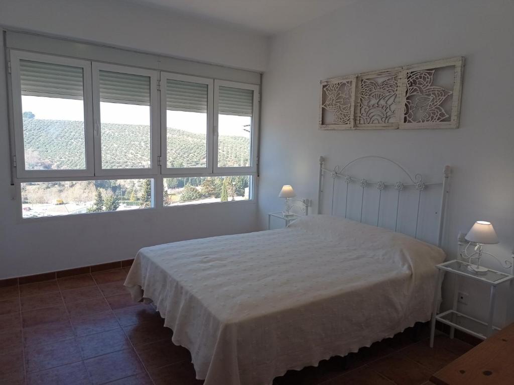 um quarto branco com uma cama e 2 janelas em EL RINCÓN DE BLASA em Cazorla