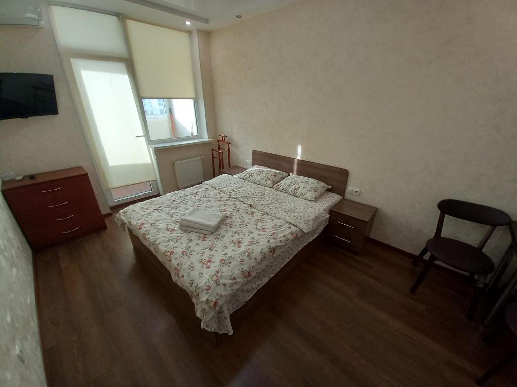 キーウにあるSmart Apartments Drahomanovaのベッドルーム1室(ベッド1台、椅子、窓付)