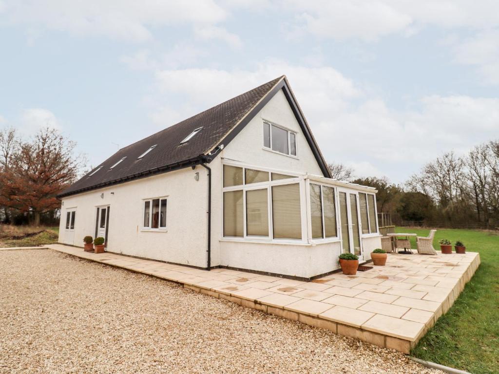 a white house with large windows and a patio at Tree Tops in Witney