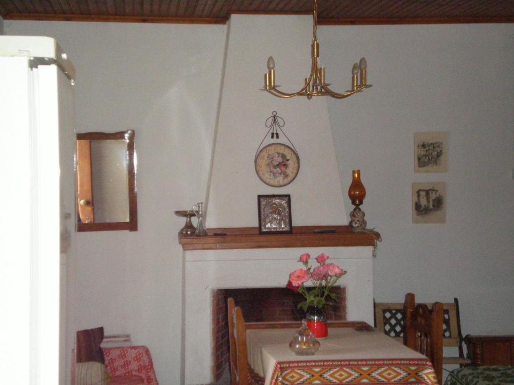 a dining room with a fireplace with a table and a clock at Archontiko Samara in Áno Lekhónia