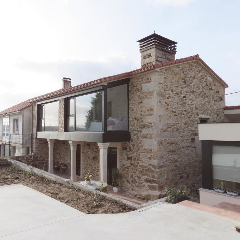 Casa de ladrillo con grandes ventanas de cristal en Casa Leonor de Aurora, en Zas