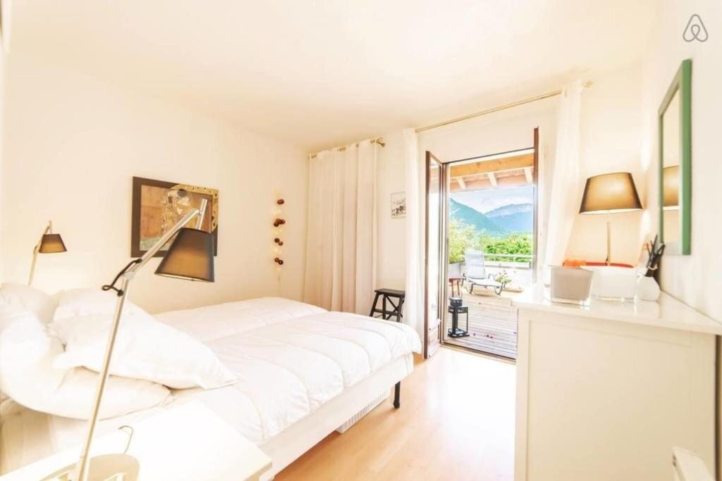 a white bedroom with a bed and a balcony at Amélia Appartement Saint-Jorioz in Saint-Jorioz