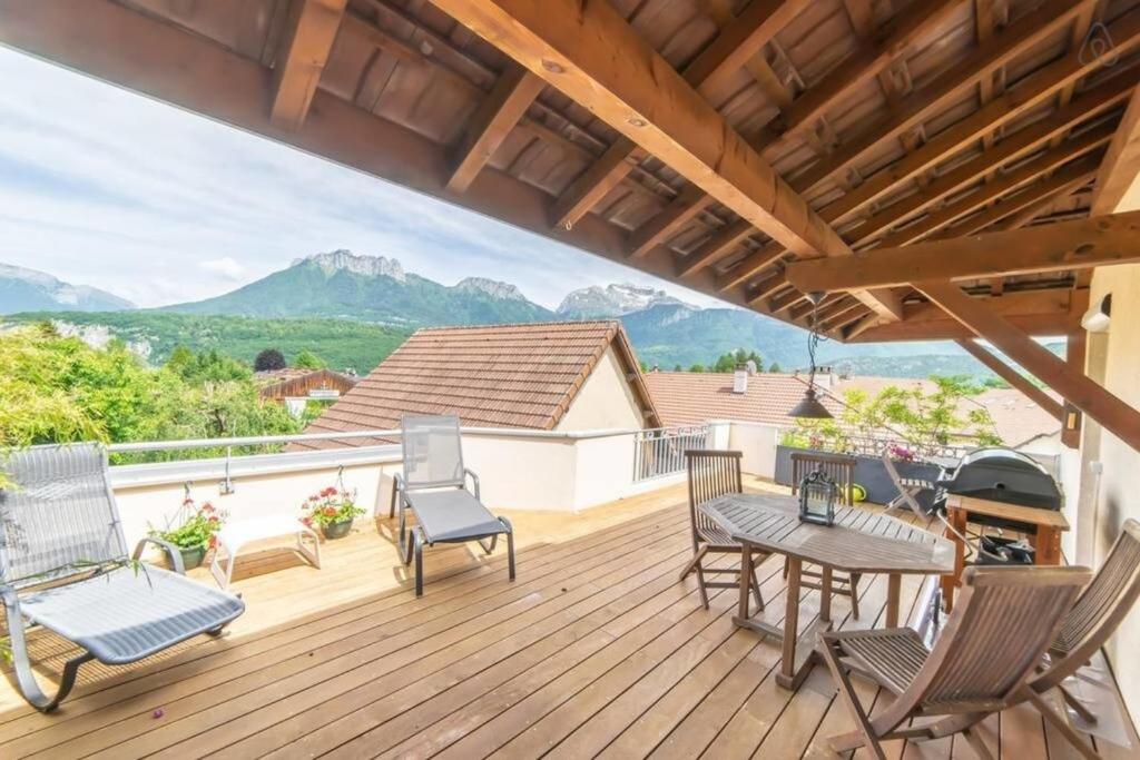 a deck with chairs and a table with a view of mountains at Amélia Appartement Saint-Jorioz in Saint-Jorioz