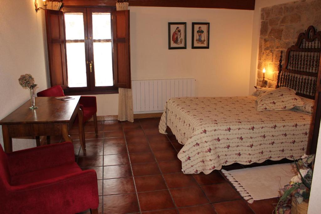 a bedroom with a bed and a desk and a window at Casa Rural El Meson in Briones