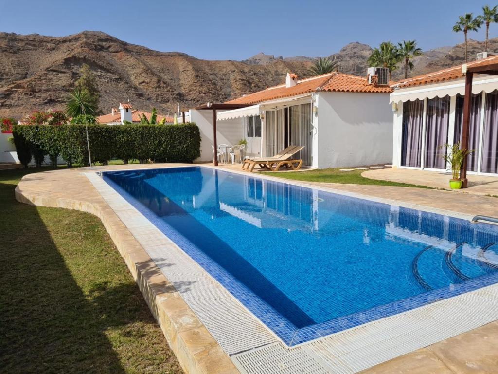 - une piscine en face d'une maison avec une montagne dans l'établissement Apartamento relax Tauro, à Mogán