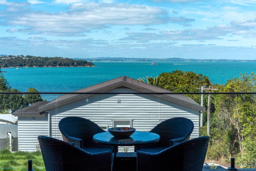 una mesa y sillas en un patio con vistas al agua en Luna Cottage. Stunning ocean views on Waiheke en Oneroa