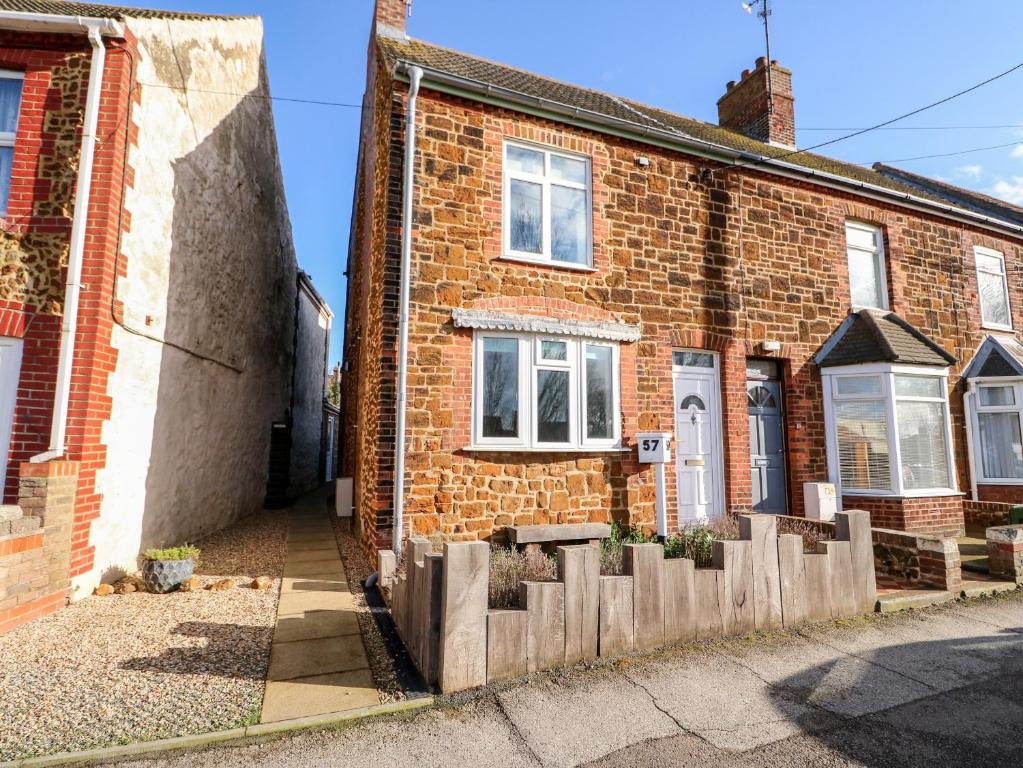 una casa de ladrillo con una valla de madera delante de ella en 57 Southend Road, en Hunstanton