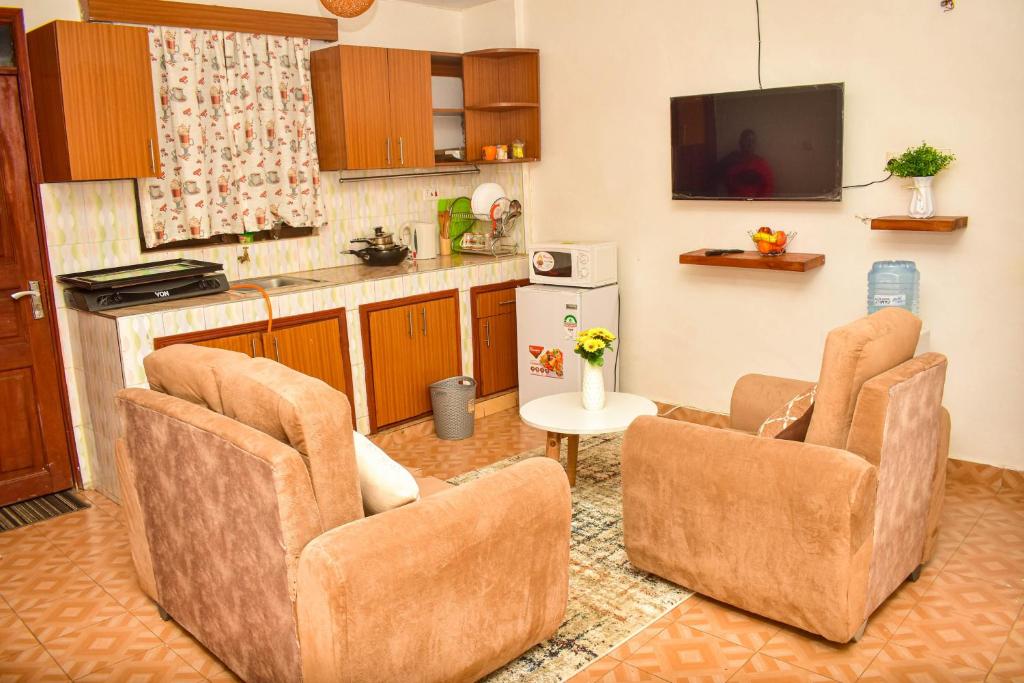 a living room with two chairs and a kitchen at Unique, Compact Studio Apartment in Kisumu