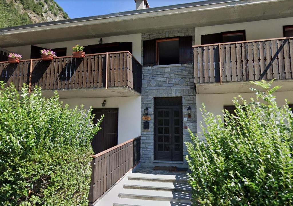 una casa con balcone, porta e alcuni cespugli di Appartamento Antey Saint André posizione centrale ad Antey-Saint-André