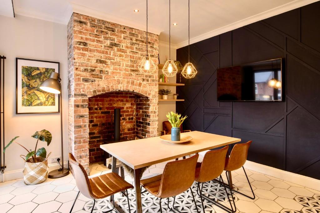 a dining room with a table and a brick fireplace at Sea Retreats, Whitley Bay, Sleeps 8 in Whitley Bay